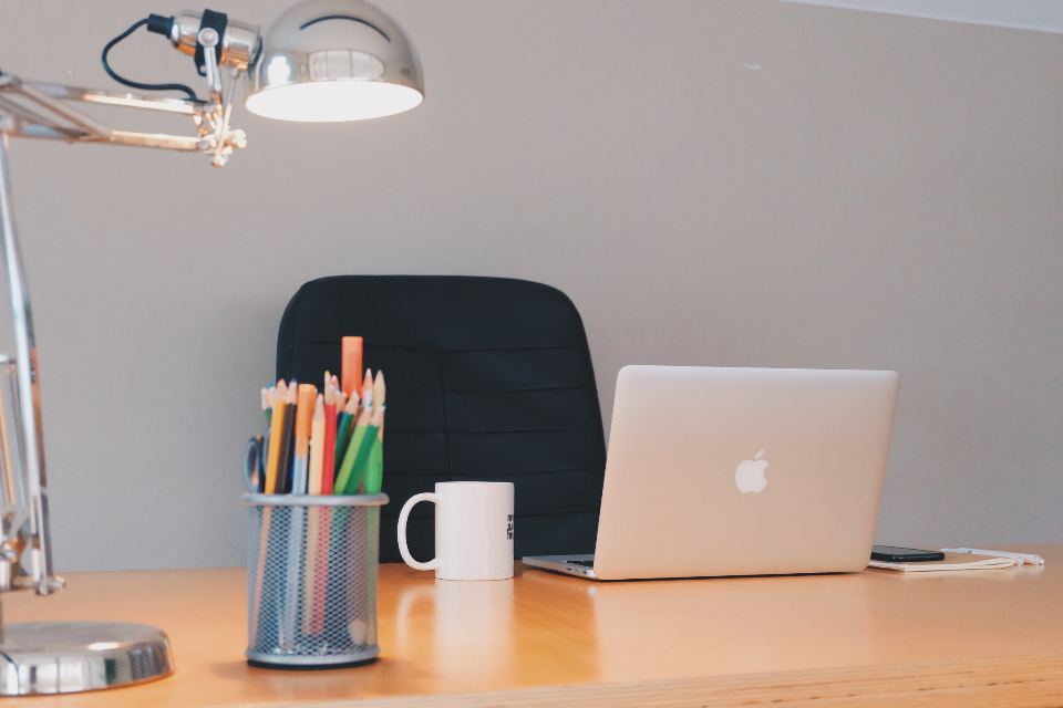 Desk with a lamp, laptop and pencil holder in soft light