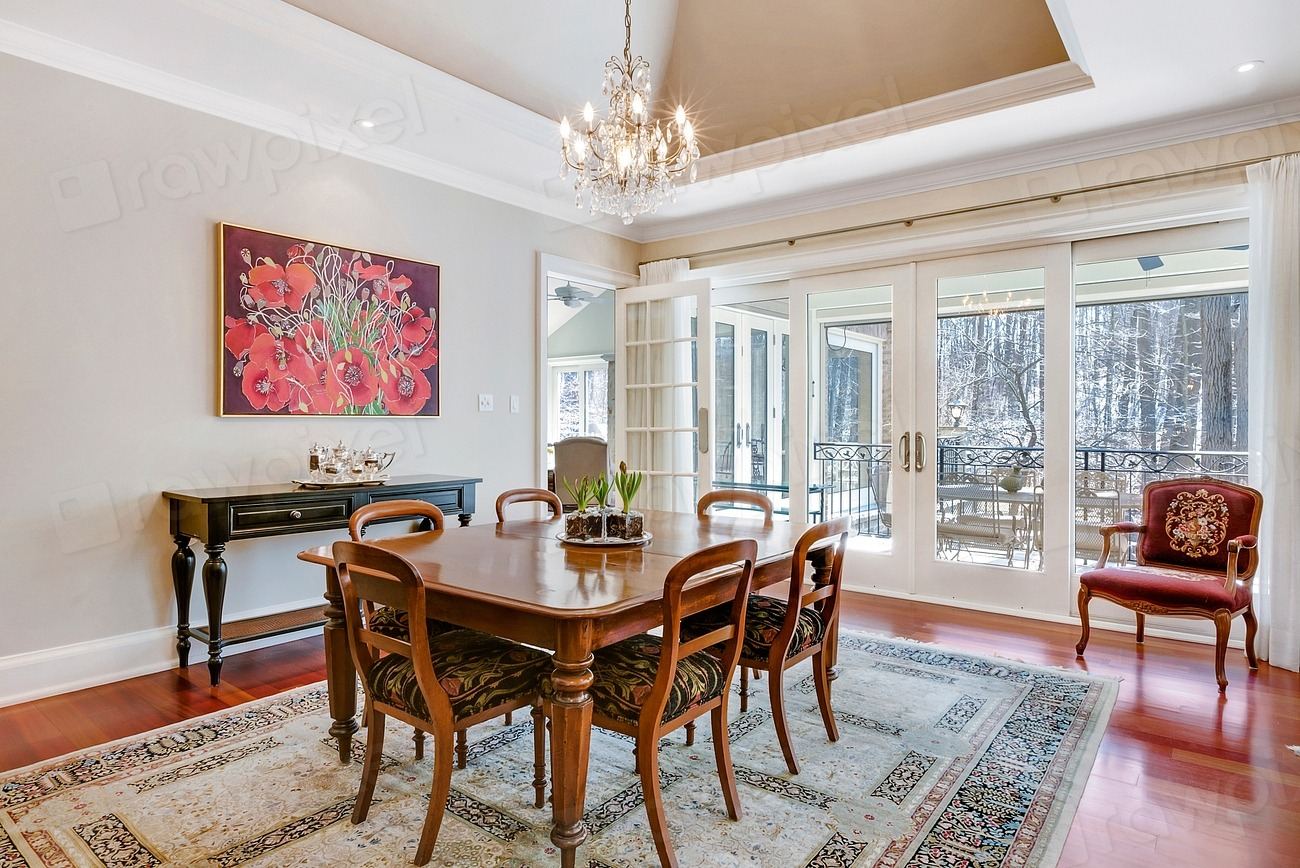 Warm dining room with a wooden table, chandelier and garden views