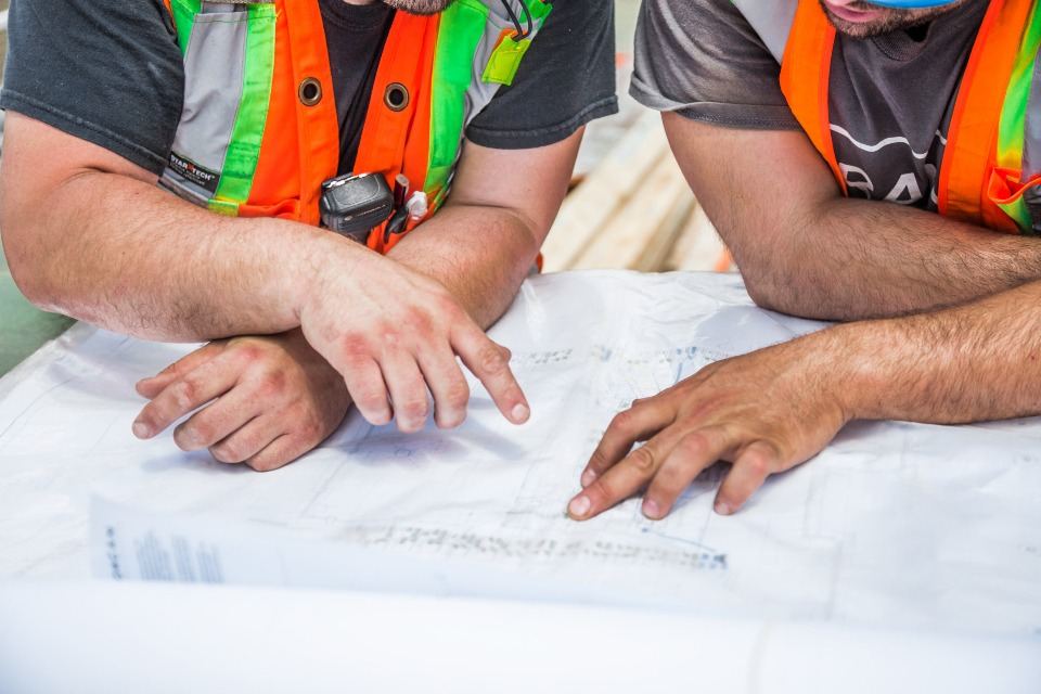 Engineers reviewing construction drawings together on site