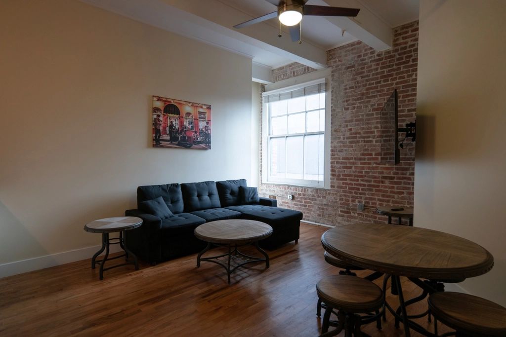 Apartment living area with a dark sofa, round coffee tables and dining stools