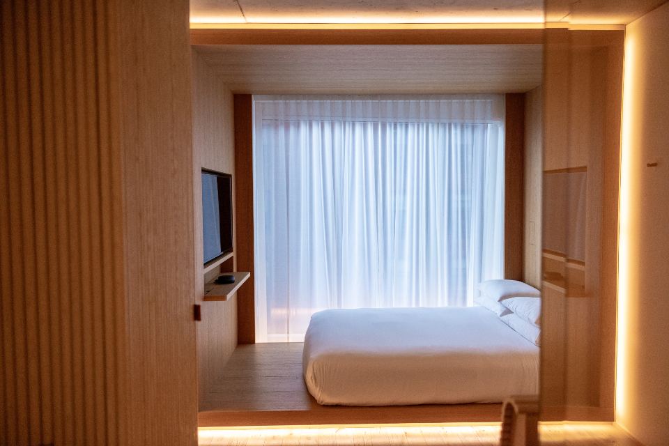 Minimal bedroom framed by warm wood panelling and soft cove lighting