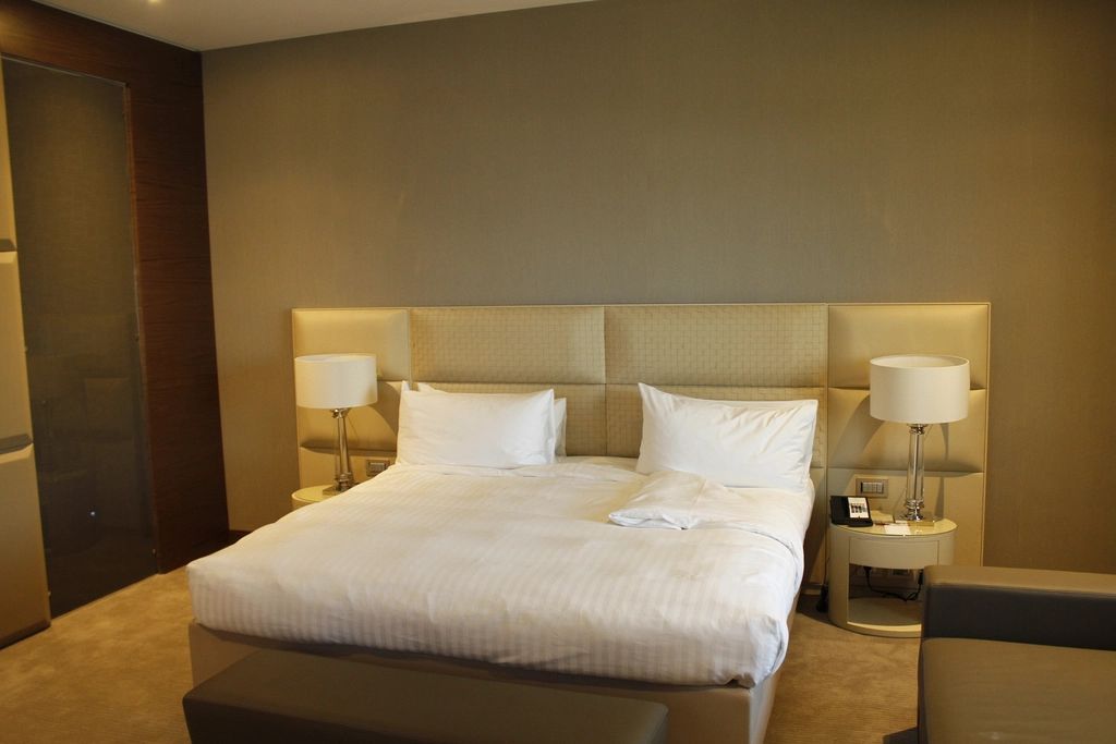 Hotel-style bedroom with a padded headboard and bedside lamps