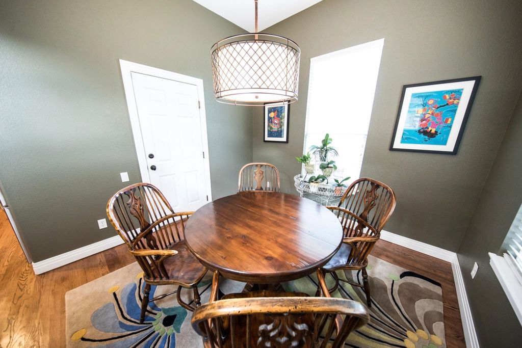 Dining room with a round wooden table, chairs and a pendant light