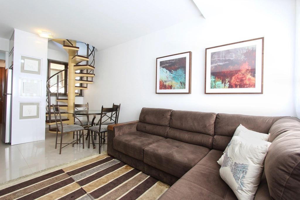 Open living and dining area with a large sofa, colourful art and a striped rug