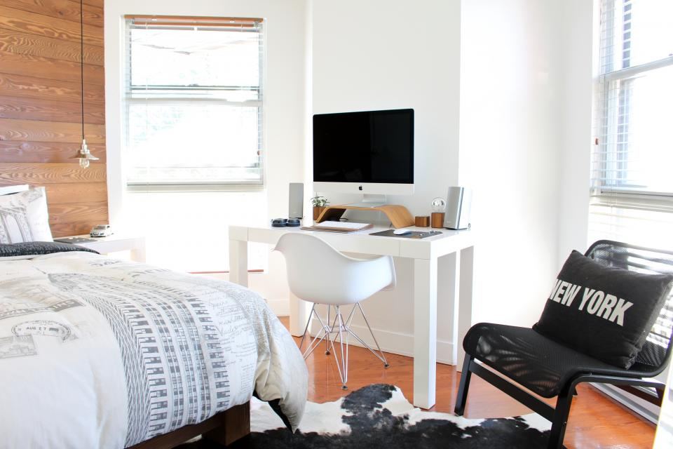 Compact bedroom with a white study desk beside the bed