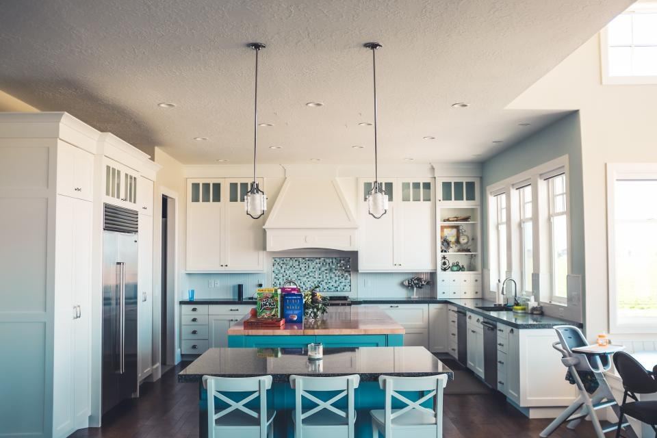 White modular kitchen with an island, pendant lights and tall storage