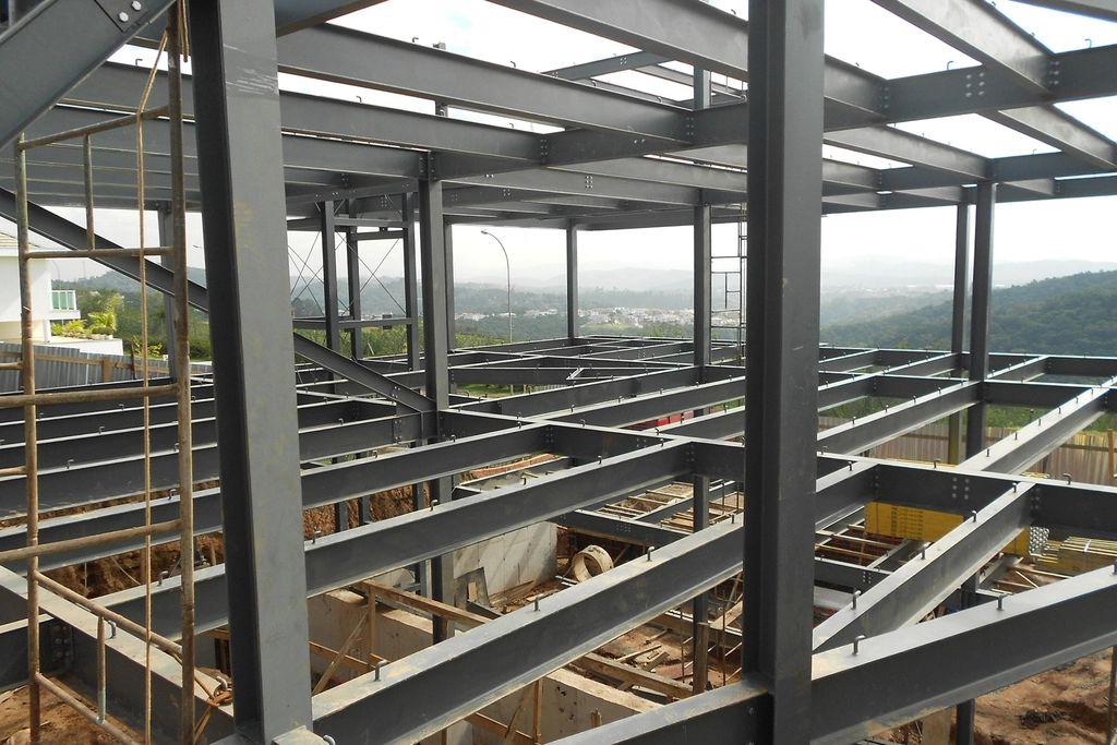 Steel frame of a pre-engineered building under construction with hills in the background